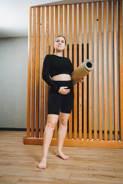 Sporty w czasie ciąży Wesoła młoda kobieta w ciąży uprawiająca sporty na macie sportowej Zdrowy styl życia w czasie ciąży