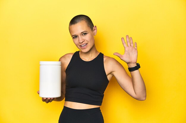 Sportystka z białkowym shake żółtym tłem w studiu uśmiechnięta cheerfu