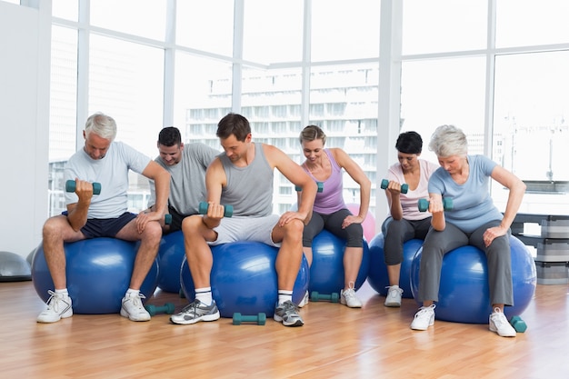 Sprawności Fizycznej Klasa Z Dumbbells Siedzi Na ćwiczenie Piłkach W Gym