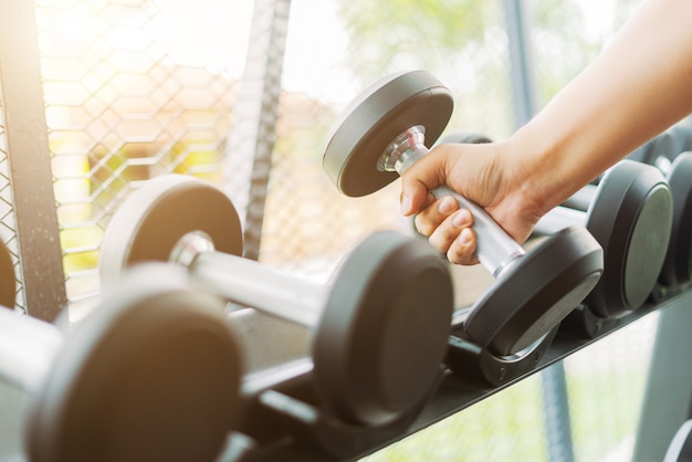 Zdjęcie sprawności fizycznej kobieta w szkoleniu pokazuje ćwiczenia z dumbbells w gym