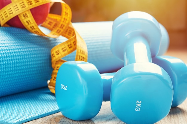 Sprawności fizycznej pojęcie z błękitnymi dumbbells, sprawności fizycznej matą i pomiarową taśmą, zamyka up