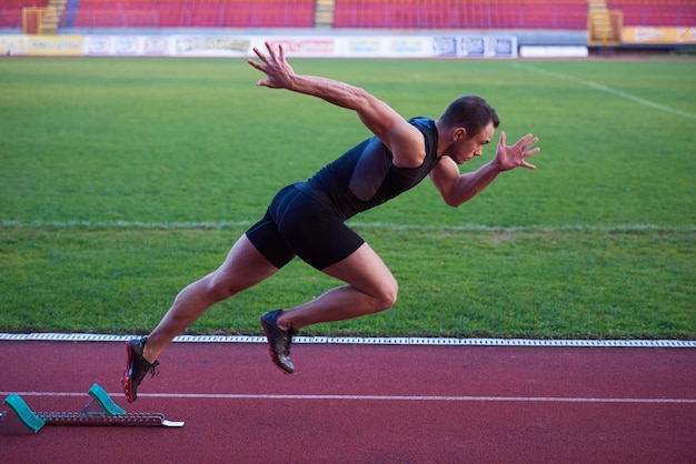 Sprinter zostawiający bloki startowe na bieżni. Wybuchowy początek.