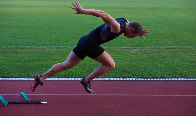 Sprinter zostawiający bloki startowe na bieżni. Wybuchowy początek.