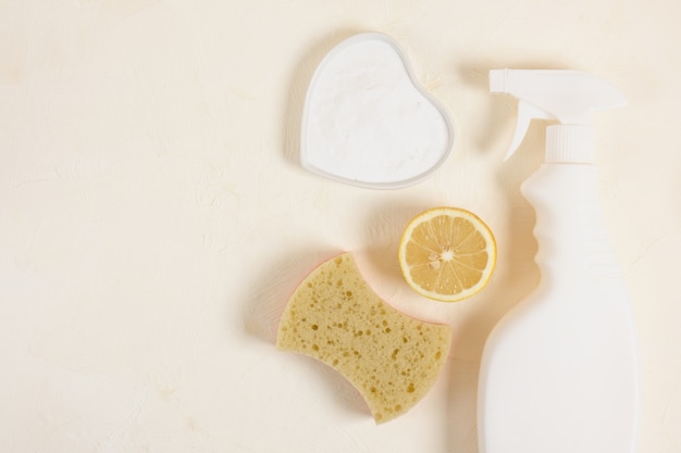 Spryskaj butelkę, gąbkę, cytrynę i sodę na beżowym spodku z sodą oczyszczoną. nietoksyczny detergent do czyszczenia