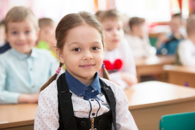 Sprytny przedszkolak przy biurku Sześcioletnia dziewczynka na tle klasy