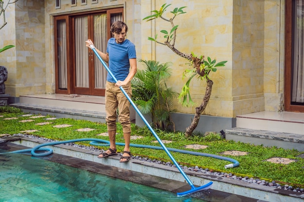 Sprzątacz basenu Mężczyzna w niebieskiej koszuli ze sprzętem do czyszczenia basenów Usługi sprzątania basenu