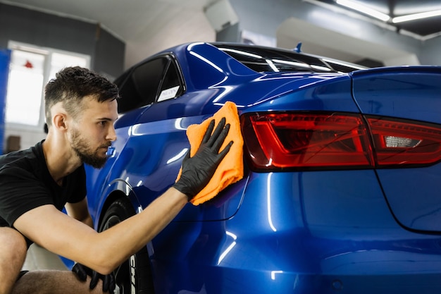 Sprzątacz pracownik suchy samochód po umyciu samochodu Ręczne suszenie samochodu za pomocą mikrofibry w detailingu auto service