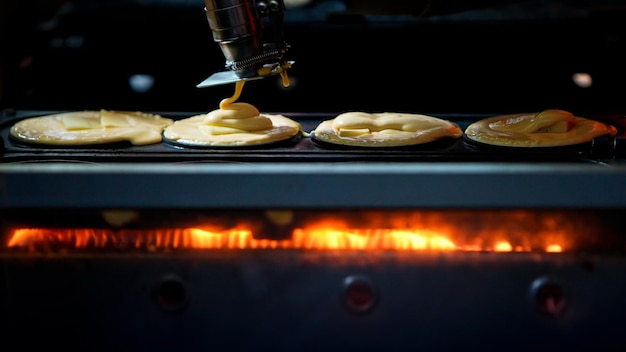 Sprzedawca gotujący dorayaki wlewający ciasto do metalowej formy japońskich naleśników