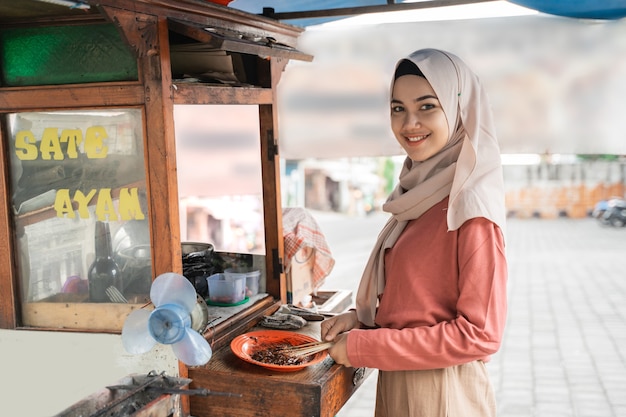 Sprzedawca Ulicznego Jedzenia Z Straganem Z Indonezyjskim Kurczakiem Satay Gotującym Na Gorącym Grillu Na Węgiel Drzewny