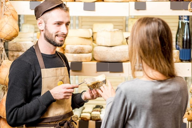 Sprzedawca z klientką wybierającą ser do zakupu w sklepie spożywczym