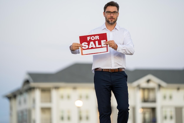 Sprzedawcy domów agenci nieruchomości trzymają znak na sprzedaż osiedli mieszkaniowych w projekcie kupna i sprzedaży