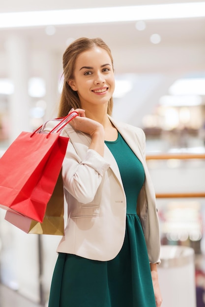 sprzedaż, konsumpcjonizm i koncepcja ludzi - szczęśliwa młoda kobieta z torbami na zakupy w centrum handlowym