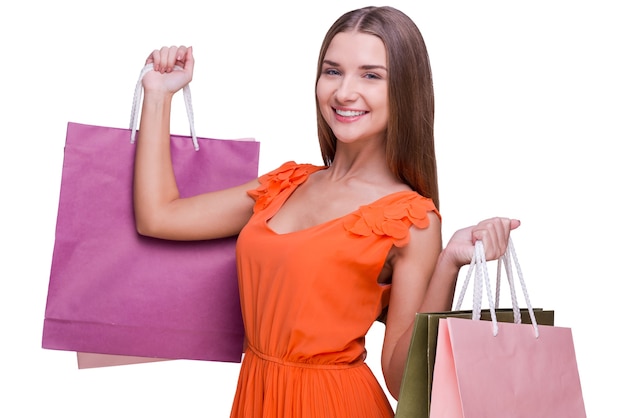 Sprzedaż! Piękna młoda kobieta trzymająca torby na zakupy i uśmiechnięta stojąc na białym tle