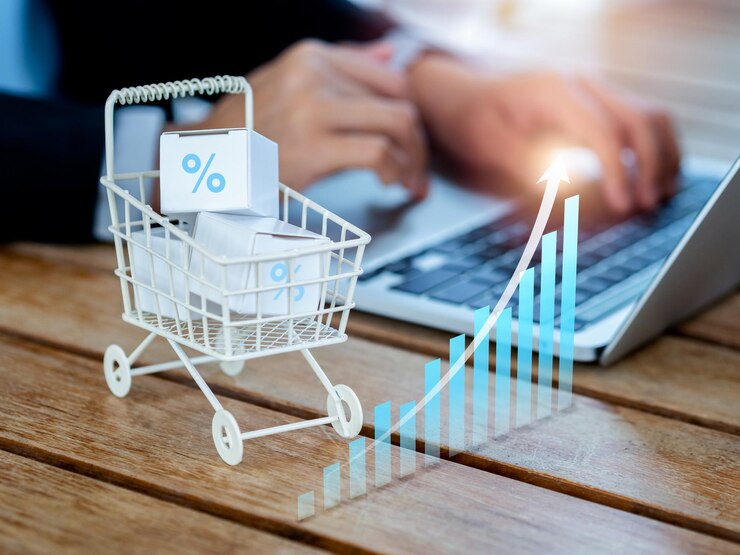 Sprzedaż zakupów online zwiększa koncepcje trendów rynkowych Rosnąca strzałka na wykresie wzrostu biznesu w pobliżu wózka na zakupy z paczkami na biurku w pobliżu osoby korzystającej z laptopa