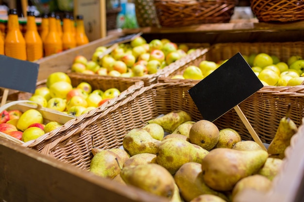 sprzedaż, zakupy, wegetariańska i ekologiczna koncepcja żywności - owoce w koszach z tabliczkami znamionowymi na bio market