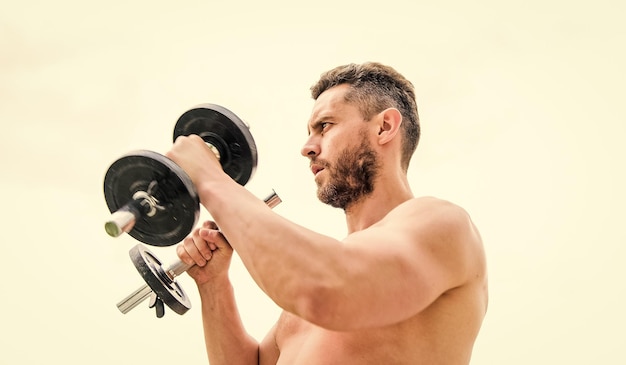 Sprzęt fitness i sport atletyczne ciało Hantle gym man sportowiec z silnymi rękami sterydy Muskularny mężczyzna ćwiczący rano z sukcesem sztangi Idealny biceps Wszystko jest możliwe