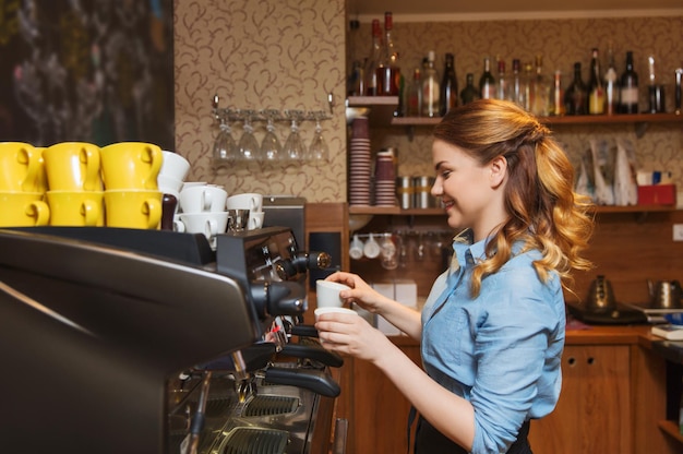 Zdjęcie sprzęt, kawiarnia, koncepcja ludzi i technologii - kobieta barista robi kawę ekspresem do kawy w kawiarni lub kuchni restauracji