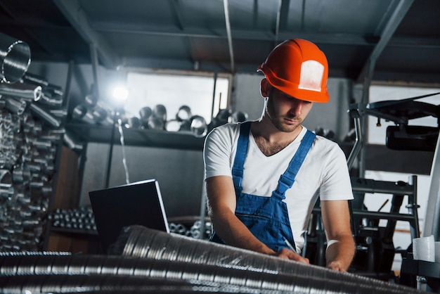 Sprzęt oświetleniowy z tyłu. Mężczyzna w mundurze pracuje nad produkcją. Nowoczesna technologia przemysłowa.