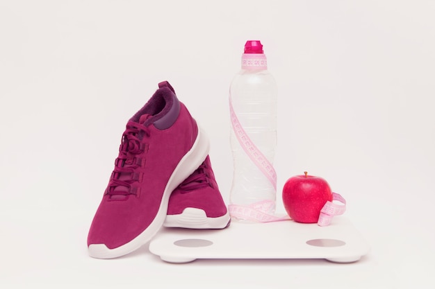 Sprzęt sportowy, jabłko i waży butelkę wody na stonowanym tle.