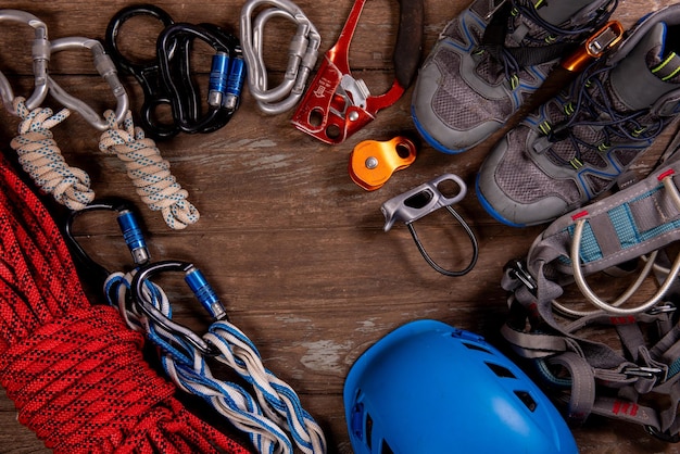 Sprzęt wspinaczkowy do alpinizmu i turystyki pieszej kask młotek karabinek buty trekkingowe i inne na drewnianym tle widok z góry