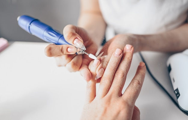 Sprzętowy proces profesjonalnego manicure, czyszczenie paznokci frezem. Zamyka w górę żeńskich ręk w piękno salonie. Leczenie paznokci paznokci, proces produkcji. Wiertarka elektryczna do paznokci w akcji