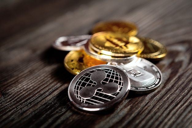 Srebne i złote monety z bitcoin, czochrą i eterum symbolem na drewnianym tle.