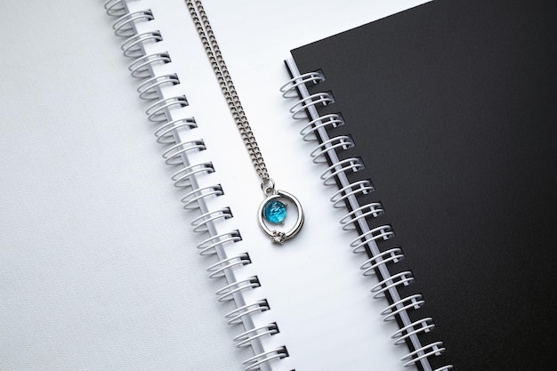 Srebrne naszyjniki łańcuszkowe z niebieskim diamentowym wisiorkiem na białym biurku