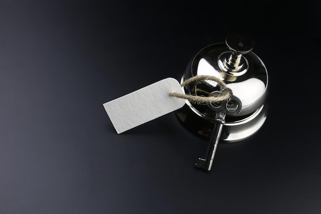 Zdjęcie srebrny dzwonek i klucz w recepcji w hotelu na czarnym tle