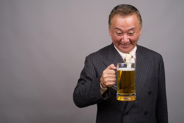 Zdjęcie Średni dorosły mężczyzna trzymający szklankę piwa na szarym tle