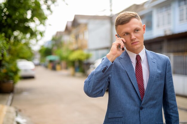 Zdjęcie Średni dorosły mężczyzna używający smartfonu na ulicy