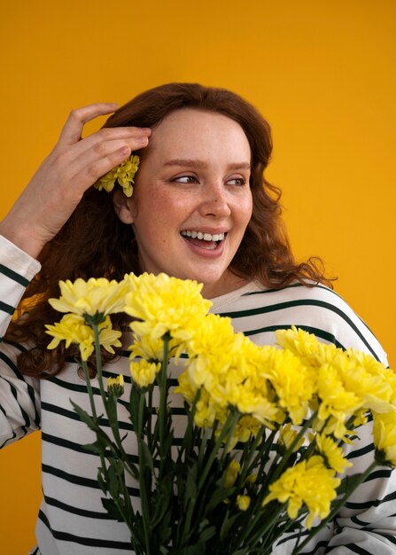 Średni strzał młoda kobieta pozuje z kwiatami