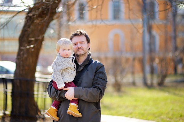 Zdjęcie Średnim wieku ojciec z synem malucha chodzić i bawić się na zewnątrz w ciepły dzień wiosny