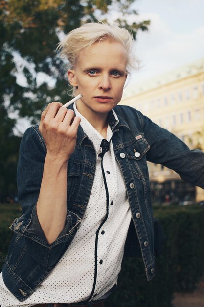 Zdjęcie Średnio dorosła kobieta trzymająca papierosa w parku