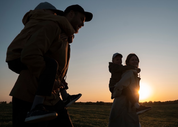 Zdjęcie Średnio strzałowa rodzinna sylwetka bawiąca się o zachodzie słońca