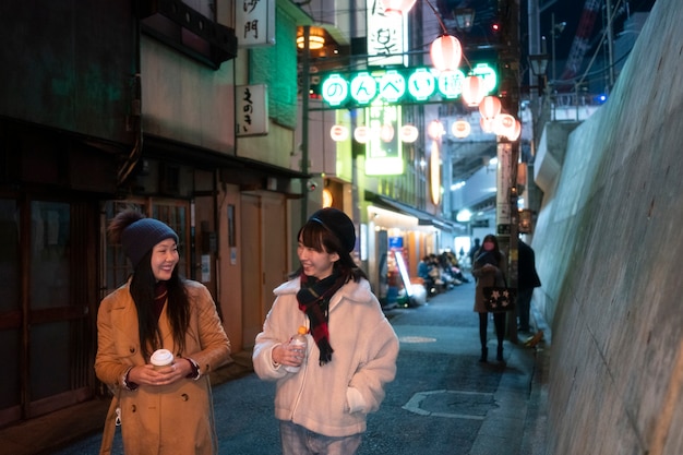 Zdjęcie Średnio strzałowe uśmiechnięte dziewczyny spacerujące razem w nocy