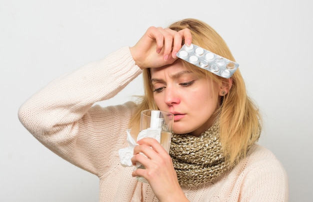 Środki na ból głowy i gorączkę. Kobieta potargane włosy szalik trzymać tabletki blister. Wytyczne dotyczące leczenia gorączki. Zażywaj leki zmniejszające gorączkę. Najlepszy reduktor gorączki. Dziewczyna cierpi na bóle głowy i zażywa lekarstwa.