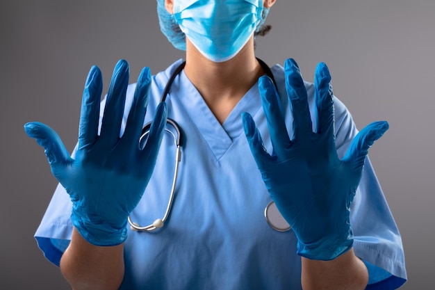 Środkowa część chirurga w rękawiczkach chirurgicznych na szarym tle