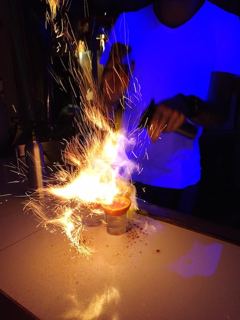 Zdjęcie Środkowa część człowieka z ogniem robiącego napoje w barze