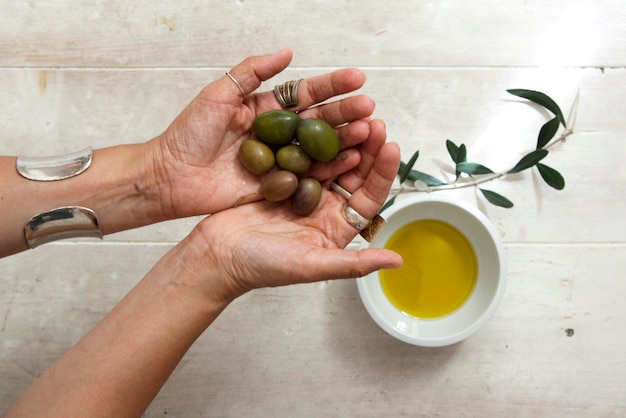 Zdjęcie Środkowa część kobiety trzymającej oliwę i miskę z oliwą z oliwek
