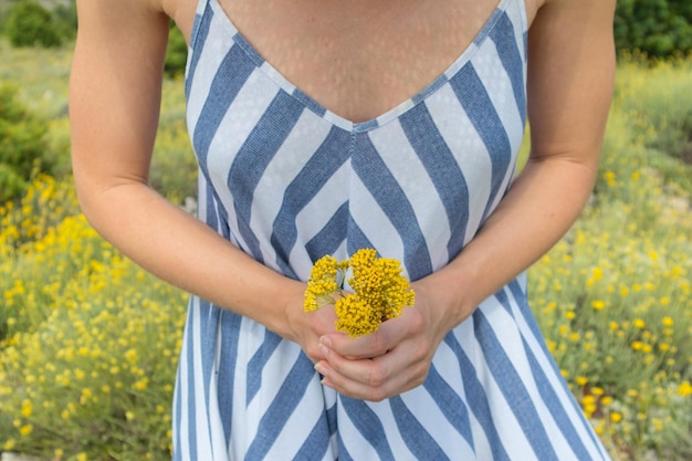 Środkowa część kobiety trzymającej żółte kwiaty