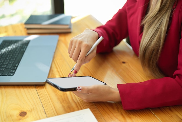 Zdjęcie Środkowa część kobiety używającej telefonu komórkowego siedzącej na stole