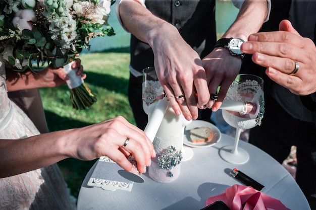 Środkowa część ludzi zapalających świecę podczas ceremonii ślubnej