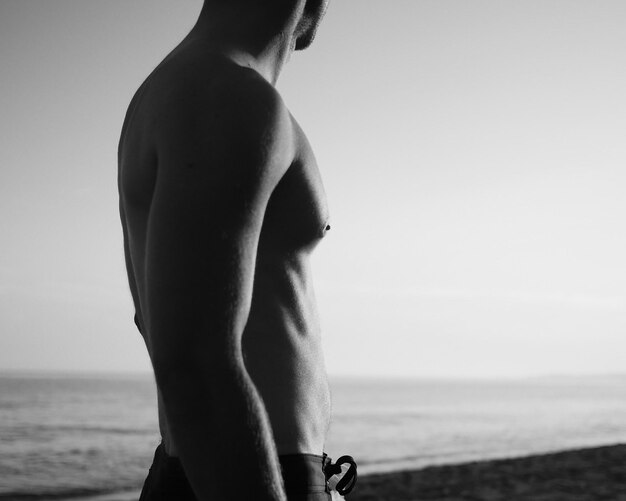 Zdjęcie Środkowa część mężczyzny bez koszuli stojącego na plaży przed niebem