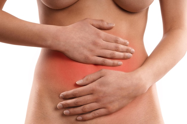 Środkowa część nagiej kobiety z bólem brzucha na białym tle