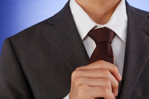 Zdjęcie Środkowa sekcja biznesmena dostosowującego krawat na niebieskim tle