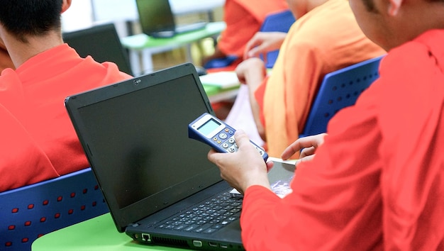 Zdjęcie Środkowa sekcja chłopca trzymającego kalkulator przy laptopie na biurku w klasie