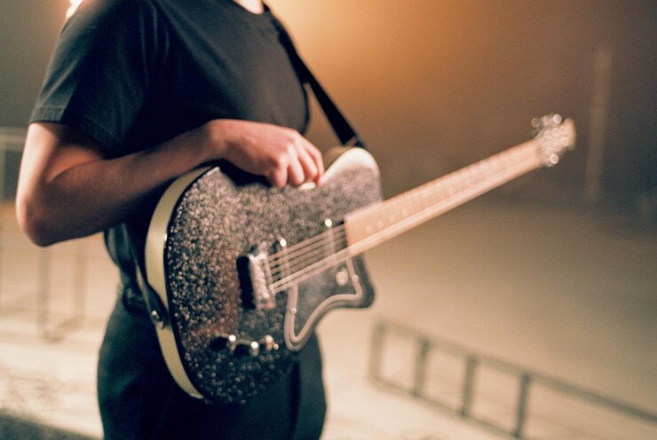 Zdjęcie środkowa sekcja człowieka grającego na gitarze na scenie