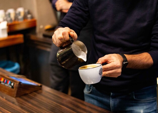 Zdjęcie Środkowa sekcja człowieka nalewającego kawę do filiżanki