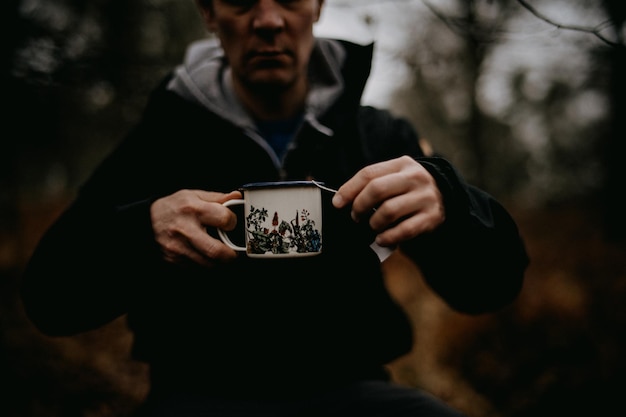 Zdjęcie Środkowa sekcja człowieka trzymającego kubek w lesie