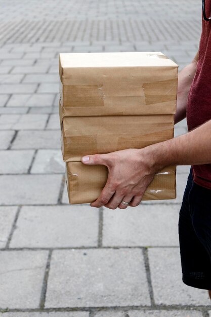 Zdjęcie Środkowa sekcja człowieka trzymającego pudełka na ulicy